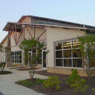 A modern building exterior with large windows and landscaped surroundings.