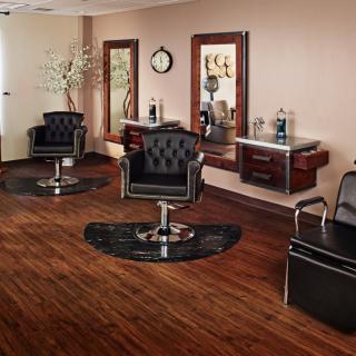 A stylish and modern hair salon interior with black leather chairs and large mirrors.