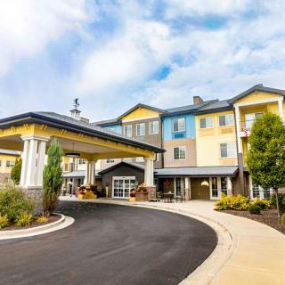 A view of a hotel entrance with a covered driveway and landscaped surroundings.