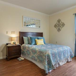A cozy bedroom with a neatly made bed, nightstand, and decorative wall art.