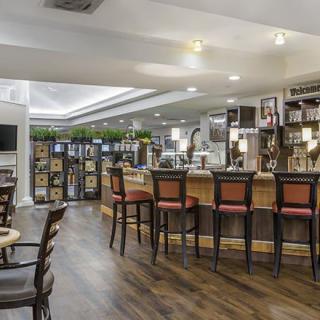 A modern bar and restaurant interior with sleek wooden flooring, a well-lit counter, and comfortable seating.