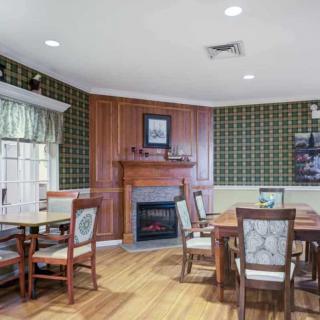 A cozy dining room with wooden flooring, a fireplace, and elegant wallpaper.