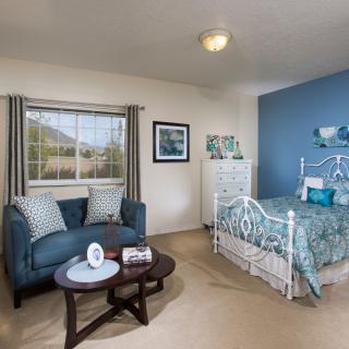 A cozy bedroom with a blue and white theme featuring a comfortable sofa and a decorative bed.