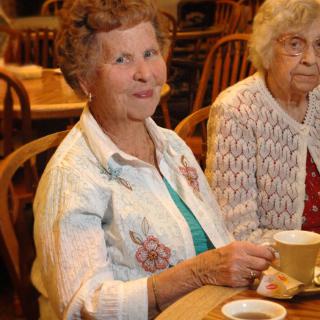 Two elderly women enjoying tea in a cafe.