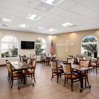 A modern dining room with neatly arranged tables and chairs, featuring a television and an American flag.