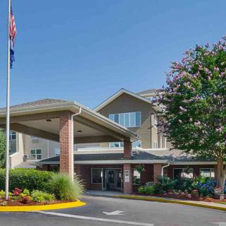A welcoming building entrance with a flagpole and landscaped surroundings.