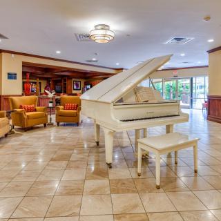 A modern hotel lobby featuring a white grand piano and a comfortable seating area.