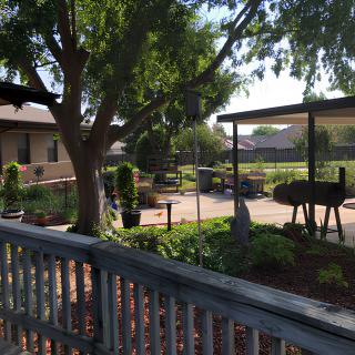 A tranquil garden patio area with trees and outdoor furniture under a clear sky.
