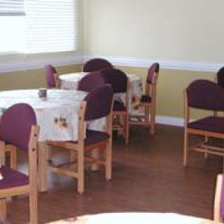 An empty dining area with several tables and chairs, covered with tablecloths.