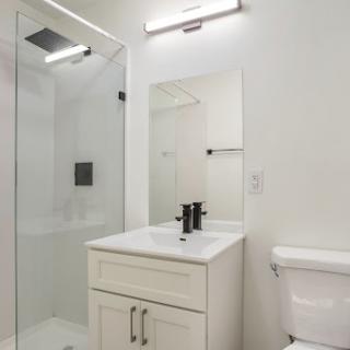 A modern bathroom featuring a sleek design with a shower, sink, and toilet.