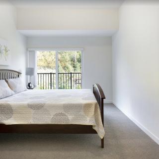 A minimalist bedroom with a bed near a large window allowing natural light inside.