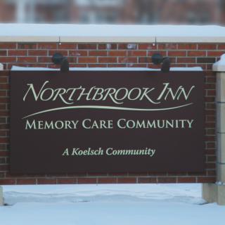 Sign for Northbrook Inn Memory Care Community, located in a snowy setting.
