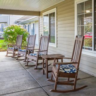 A cozy porch with wooden rocking chairs and floral cushions, providing a welcoming outdoor seating area.