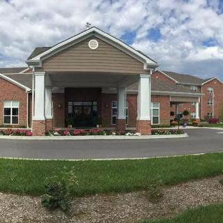 A large brick building with a prominent entrance and well-maintained landscaping under a partly cloudy sky.