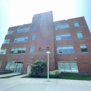A modern brick building with large windows and a landscaped entrance.
