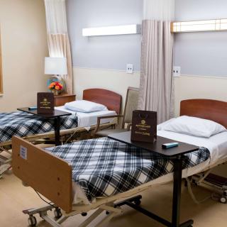 A well-organized hospital room with two neatly made beds, equipped with bedside tables and surrounded by a clean, welcoming environment.