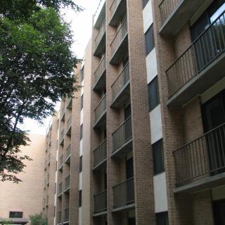 A multi-story residential apartment building with balconies and nearby trees.