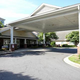 A building entrance with a covered driveway and landscaped surroundings.