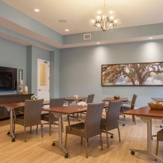 A modern conference room with tables and chairs, a television, and artwork on the wall.