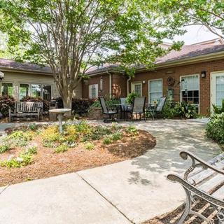 A peaceful courtyard with a garden and seating area surrounded by trees.