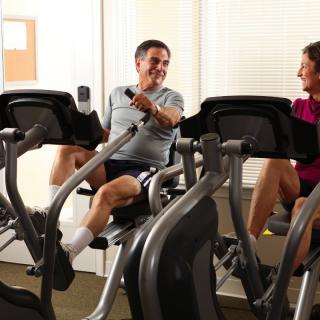 Two people exercising on stationary bikes in a gym.