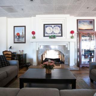 A cozy living room featuring a central fireplace, surrounded by comfortable sofas and decorated with artwork and plants.