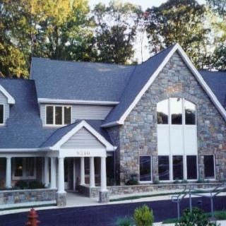 A large residential home with a stone facade and multiple windows surrounded by trees.