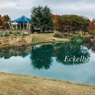 A serene park scene with a pavilion overlooking a calm lake surrounded by trees.