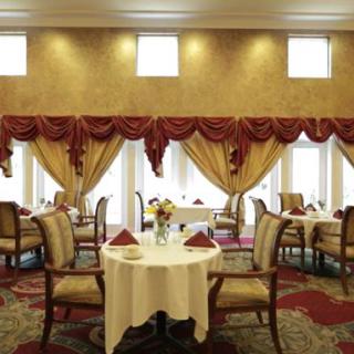 Elegant dining area with beautifully arranged tables and chairs, draped with luxurious curtains.