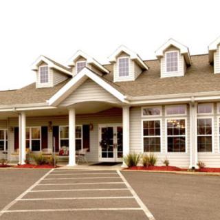 A large building with multiple windows and a parking lot in front.