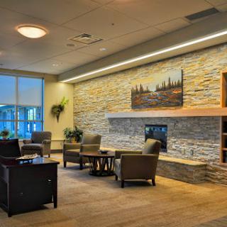 A welcoming and modern lounge area featuring comfortable seating, a stone accent wall, and a cozy fireplace.