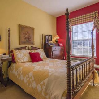 A cozy bedroom with a four-poster bed, featuring vibrant red and yellow walls.