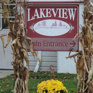A sign for the Lakeview Main Entrance surrounded by corn stalks and yellow flowers.