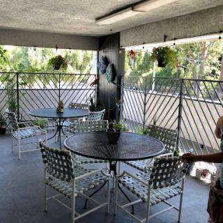A cozy outdoor patio area with tables, chairs, and lush plants.