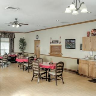 A cozy dining room with neatly arranged tables and chairs, illuminated by overhead lights.