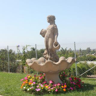 A garden fountain with a statue surrounded by colorful flowers.