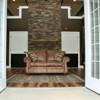 A stylish living room with a brown leather sofa centered between open double doors, showcasing modern interior decor.