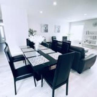 A modern dining area with black chairs and a sleek dining table in an open living space.