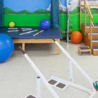 A physical therapy room equipped with exercise tools such as fitness balls, parallel bars, and a small staircase for rehabilitation exercises.
