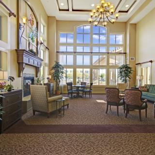 A spacious and well-lit lobby with large windows, comfortable seating, and a central chandelier.