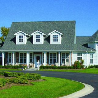 A large, two-story residential home with a spacious lawn and circular driveway.