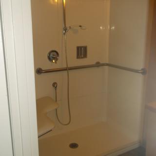A bathroom shower with handrails and a showerhead.