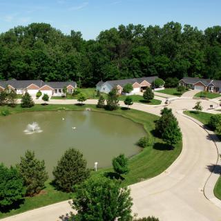 Aerial view of a suburban neighborhood with houses surrounding a pond with a fountain.