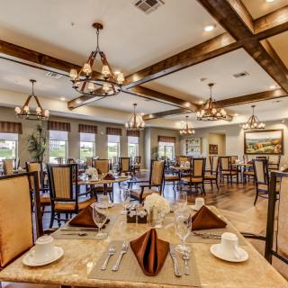 An elegant dining area with neatly arranged tables and decorative chandeliers.