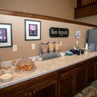 A breakfast buffet setup featuring cereal dispensers, snacks, and beverages on a kitchen counter.