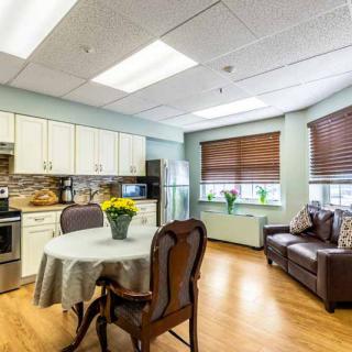 A cozy kitchen and dining area featuring a table with chairs, a sofa, and an array of kitchen appliances in a well-lit room.