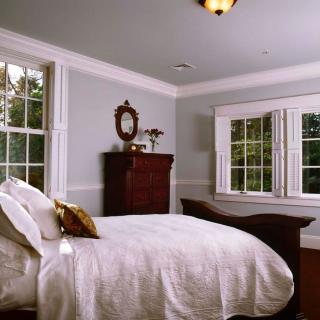 A classic bedroom with a cozy bed and bright natural lighting.