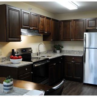 A modern kitchen with dark wood cabinets and stainless steel appliances.