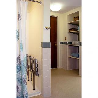 A bathroom featuring an open shower, neatly organized towels on shelves, and a wooden door.
