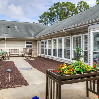 A cozy courtyard with seating, planters, and large windows.